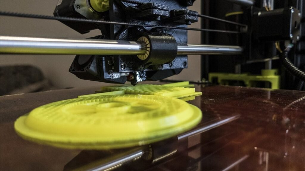 Druckkopf eines 3D-Druckers über einem gelben, ringförmigen Druckteil auf der Glasplatte